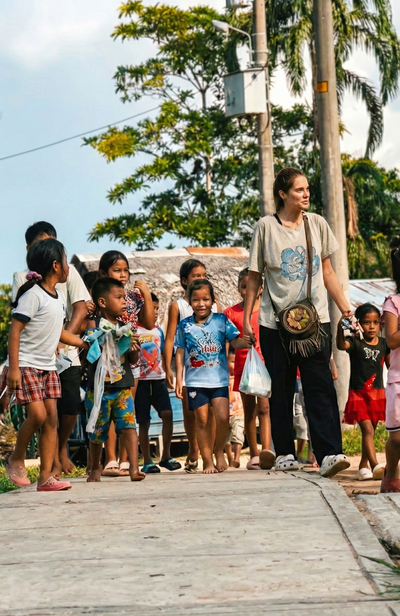 Woman walking with a group of children on a street